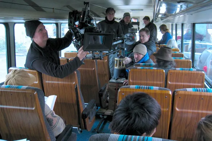 Keith Thompson operates the camera jib down the aisle of a bus.